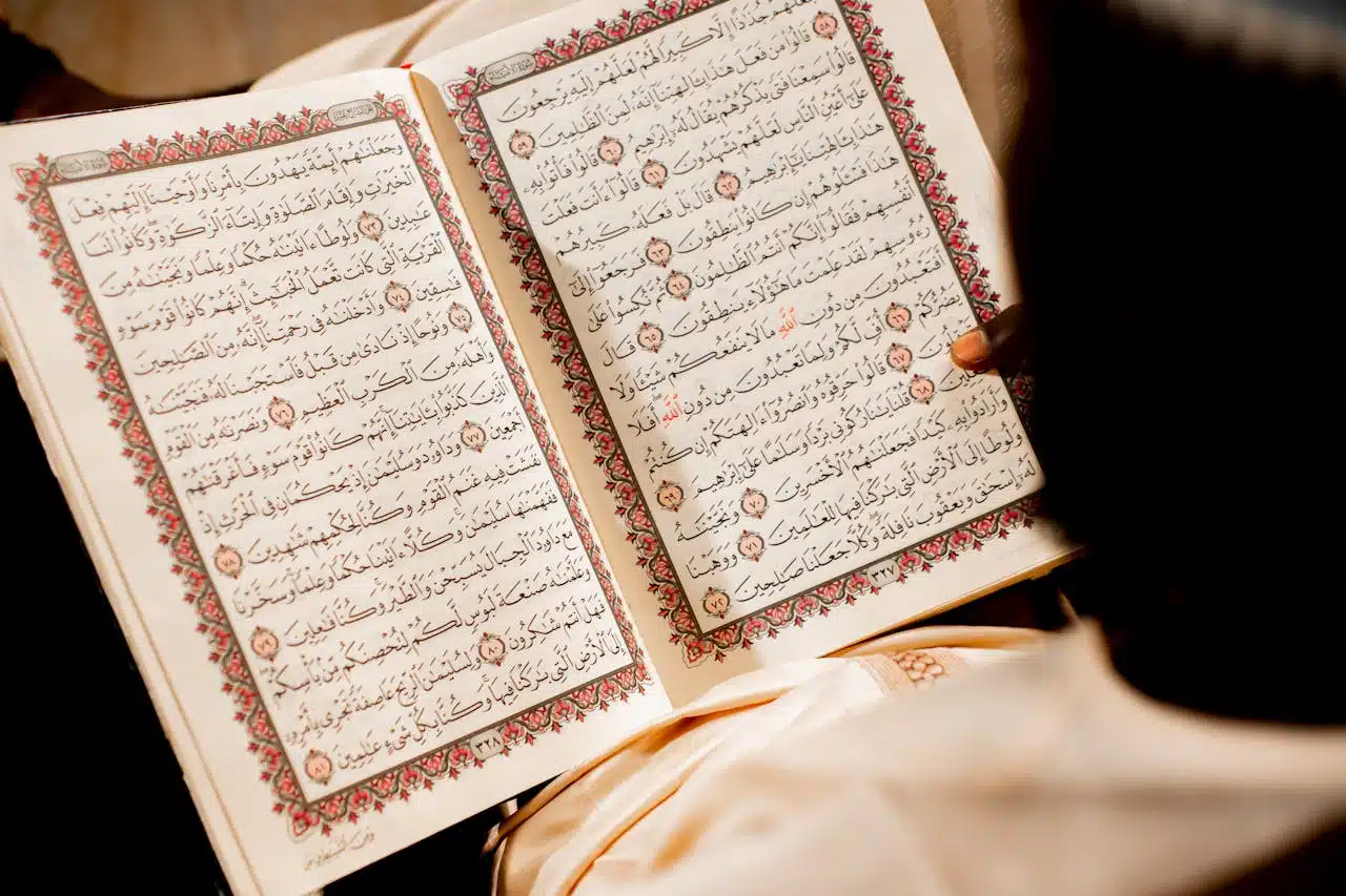 about-us A person reading an open Quran, focusing on religious text and spiritual reflection.